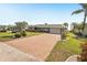 Charming single-story home featuring a brick-accented facade, lush landscaping, and a spacious brick-paved driveway at 1405 W Del Webb Blvd, Sun City Center, FL 33573