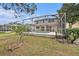 View of the rear of the home featuring a screened-in pool and lush backyard at 1719 Bayhill Dr, Oldsmar, FL 34677