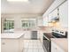 Updated kitchen features stainless dishwasher, white cabinets, island and view of screened patio at 1719 Bayhill Dr, Oldsmar, FL 34677