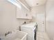 Well-lit laundry room with modern washer and dryer, utility sink, and ample storage cabinets at 1719 Bayhill Dr, Oldsmar, FL 34677