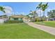 Inviting home with a well-manicured lawn, swaying palms, and a long driveway leading to a single-car garage at 1727 New Hampshire Ne Ave, St Petersburg, FL 33703