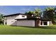 Side view of modern home boasting clean lines and a beautifully landscaped yard, perfect for outdoor enjoyment at 19207 Gunn Hwy, Odessa, FL 33556