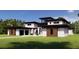 View of the contemporary home with sleek lines, a spacious front yard, and attached garages at 19207 Gunn Hwy, Odessa, FL 33556