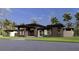 Stunning modern home with large windows and a grand entrance, surrounded by lush landscaping and palm trees at 19211 Gunn Hwy, Odessa, FL 33556