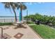 Outdoor dining area with a grill and lush landscaping next to the pool at 19910 Gulf Boulevard # 102, Indian Shores, FL 33785