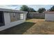 A spacious backyard featuring a wooden fence, a shed, and an enclosed patio, ideal for relaxation and outdoor activities at 2035 Erin Dr, Holiday, FL 34690