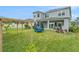 Large backyard featuring a covered patio, green grass, and a trampoline at 2693 Leafwing Ct, Palm Harbor, FL 34683