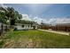 View of the backyard featuring a grassy area and wood fence, under a partly cloudy sky at 306 Banana St, Tarpon Springs, FL 34689