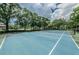 Well-maintained blue tennis court surrounded by lush greenery, perfect for recreational play at 3079 Landmark Blvd # 1608, Palm Harbor, FL 34684