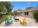 Charming backyard with a brick patio, fire pit, and colorful Adirondack chairs at 3268 Tanglewood Trl, Palm Harbor, FL 34685