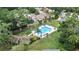 Aerial view of a fenced private pool surrounded by lush green landscaping and seating areas at 3268 Tanglewood Trl, Palm Harbor, FL 34685