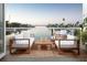 Relaxing waterfront balcony featuring comfortable white seating, wood accents, and clear glass railings at 344 Capri Blvd, Treasure Island, FL 33706