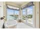 Bright bathroom with a soaking tub by a large window and glass doors to balcony, offering relaxation with canal views at 344 Capri Blvd, Treasure Island, FL 33706