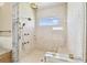 This gorgeous walk-in shower features honeycomb tile, multiple shower heads, a marble bench, and a window at 344 Capri Blvd, Treasure Island, FL 33706