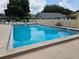 Community pool surrounded by a white fence, lounge chairs, and clear blue water for residents to enjoy at 38225 Ironwood Pl # 38225, Zephyrhills, FL 33542
