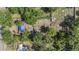 Aerial view of a tree-covered lot with a blue tarp-covered structure and scattered debris at 4815 N Falkenburg Rd, Tampa, FL 33610