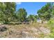 View of the property's backyard with overgrown lawn, some trees, and discarded construction debris at 4815 N Falkenburg Rd, Tampa, FL 33610