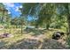 Cleared backyard with trees, a metal structure, discarded tires, and debris on a sunny day at 4815 N Falkenburg Rd, Tampa, FL 33610