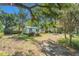 Single story home view showing the lawn, trash bins, trees, debris, and a privacy sign at 4815 N Falkenburg Rd, Tampa, FL 33610