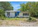 Exterior view of a weathered single-story home with a blue tarp on the roof at 4815 N Falkenburg Rd, Tampa, FL 33610