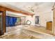 Distressed living room with worn-out flooring, outdated ceiling fan, and open doorway at 4815 N Falkenburg Rd, Tampa, FL 33610
