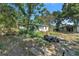 View of back of a single story home with a white exterior, overgrown yard, fence and debris at 4815 N Falkenburg Rd, Tampa, FL 33610