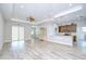 Open-concept living room featuring wood-look tile flooring, large windows and view to the kitchen at 5732 Stockport St, Riverview, FL 33578