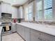 Spacious kitchen featuring gray cabinets, stainless steel appliances, and tile backsplash, with quartz countertops at 5807 Circa Fishhawk Blvd, Lithia, FL 33547