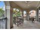 View of a balcony with a table and chairs, wrought iron railings, and arched openings framing lush greenery at 624 Balibay Rd, Apollo Beach, FL 33572