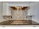 Cooktop featuring black granite countertops, tiled backsplash, a stainless steel hood, and white cabinetry at 624 Balibay Rd, Apollo Beach, FL 33572
