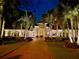 Beautifully lit Mediterranean style home at night with a long brick driveway and tropical landscaping at 624 Balibay Rd, Apollo Beach, FL 33572