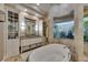 Elegant bathroom boasts a soaking tub with wood accents, a garden view, and custom cabinets at 624 Balibay Rd, Apollo Beach, FL 33572