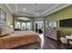 Main bedroom with sitting area, dark wood floors, tray ceilings, and sliding glass doors to the lanai at 624 Balibay Rd, Apollo Beach, FL 33572