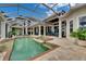 Luxury outdoor pool and spa area with a screened enclosure, travertine tile, and water views at 624 Balibay Rd, Apollo Beach, FL 33572