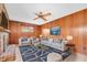 Cozy living room with a brick fireplace, wood paneling, a ceiling fan, and comfortable seating at 6638 12Th N Ter, St Petersburg, FL 33710