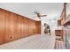 Open living area with wood paneled wall, ceiling fan, and connecting kitchen at 6638 12Th N Ter, St Petersburg, FL 33710