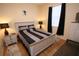Neutral bedroom features a queen-sized bed, hardwood floors, and a window with dark curtains at 7334 Night Heron Dr, Land O Lakes, FL 34637