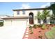 Charming two-story home with a manicured lawn, palm trees, and a paved walkway leading to the front door at 7334 Night Heron Dr, Land O Lakes, FL 34637