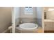 Relaxing bathroom featuring a soaking tub, tile accents, and natural light from the window at 789 Grand Cypress Ln, Tarpon Springs, FL 34689