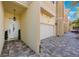 Exterior view showing a charming tan townhome featuring a two-car garage and a brick-paved driveway at 789 Grand Cypress Ln, Tarpon Springs, FL 34689