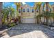 Beautiful tan townhome featuring lush landscaping, palm trees, and a brick-paved driveway at 789 Grand Cypress Ln, Tarpon Springs, FL 34689