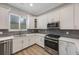 Well-lit kitchen featuring stainless steel appliances, white cabinetry, and a stylish backsplash at 789 Grand Cypress Ln, Tarpon Springs, FL 34689