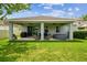 Landscaped backyard with a covered patio featuring comfortable seating, a grill, and a luxurious hot tub at 8228 Sunlit Horizon Ln, Land O Lakes, FL 34637
