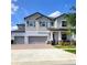 A beautiful two-story home featuring a three-car garage and well-manicured landscaping under a bright, partly cloudy sky at 11704 Navajo Sandstone St, Riverview, FL 33579