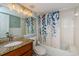 Bathroom with a shower and tub, granite countertop vanity, and leaf patterned shower curtain at 1290 Pine Ridge E Cir # G1, Tarpon Springs, FL 34688