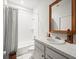 Classic bathroom with a tiled shower/tub combo, subway tile surround, and a vanity with a wooden framed mirror at 13801 Lake Village Pl, Tampa, FL 33618