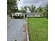 Charming single-story home featuring a well-maintained lawn, a rock driveway, and manicured shrubbery at 1412 Sunset Ln, Lutz, FL 33549