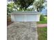 A detached two-car garage with white doors sits beside a small yard at 1412 Sunset Ln, Lutz, FL 33549