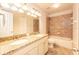 Well-lit bathroom boasts double sinks, granite countertops, and a tiled shower-tub combination for a luxurious experience at 16226 Bayberry View Dr, Lithia, FL 33547