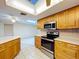 Bright kitchen featuring tile flooring, modern appliances, wooden cabinetry, and a ceiling fan at 232 Pinecrest Dr, Palm Harbor, FL 34683